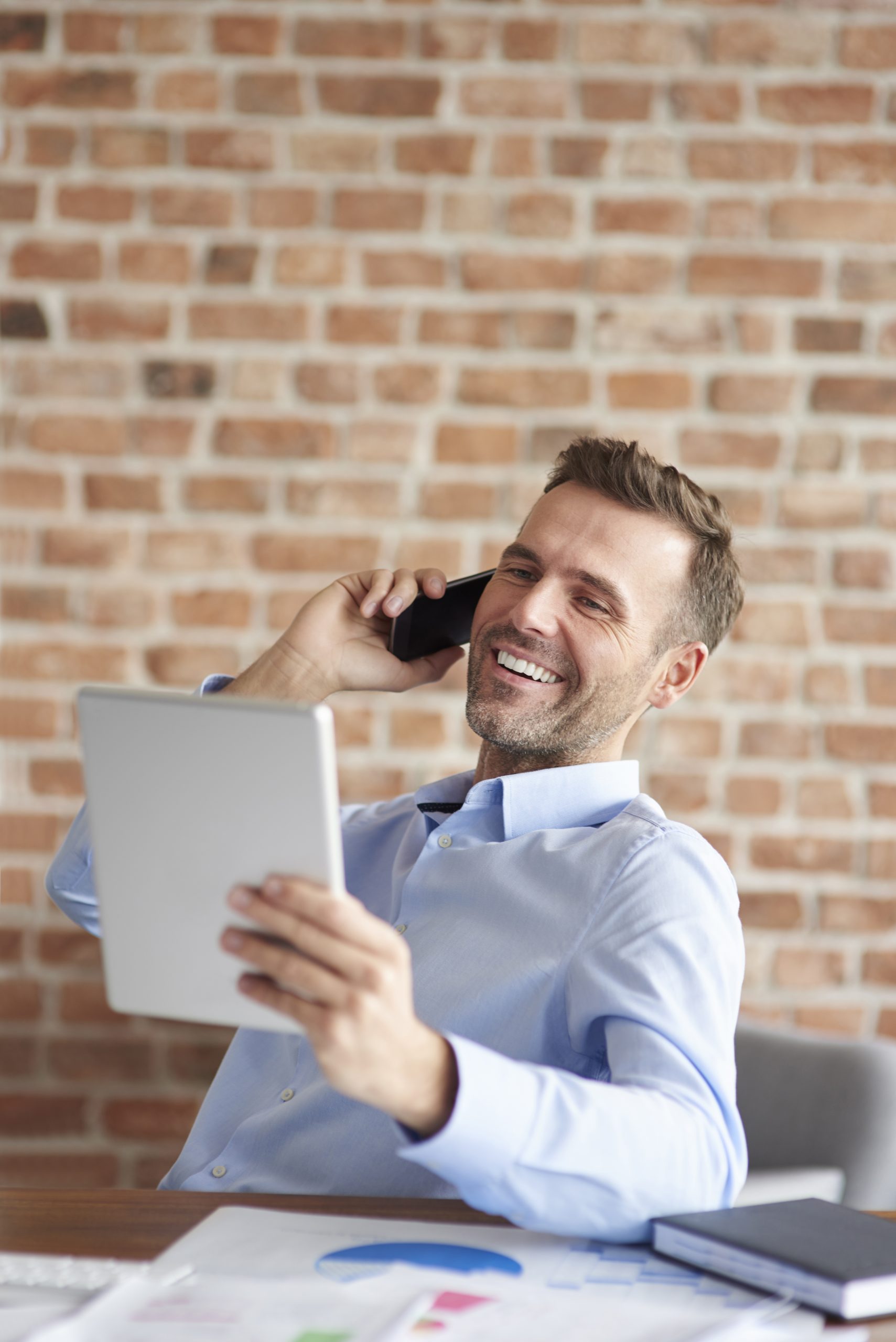 man talking phone browsing digital tablet